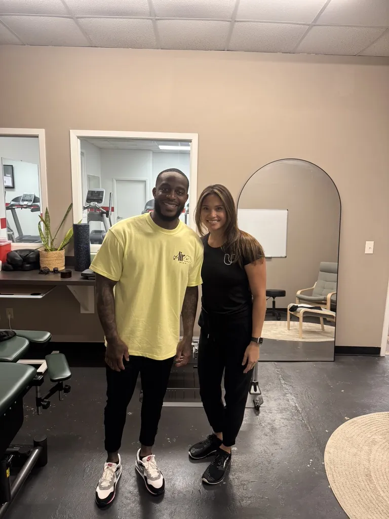 Athlete smiling with a Unify PT clinician in the treatment room
